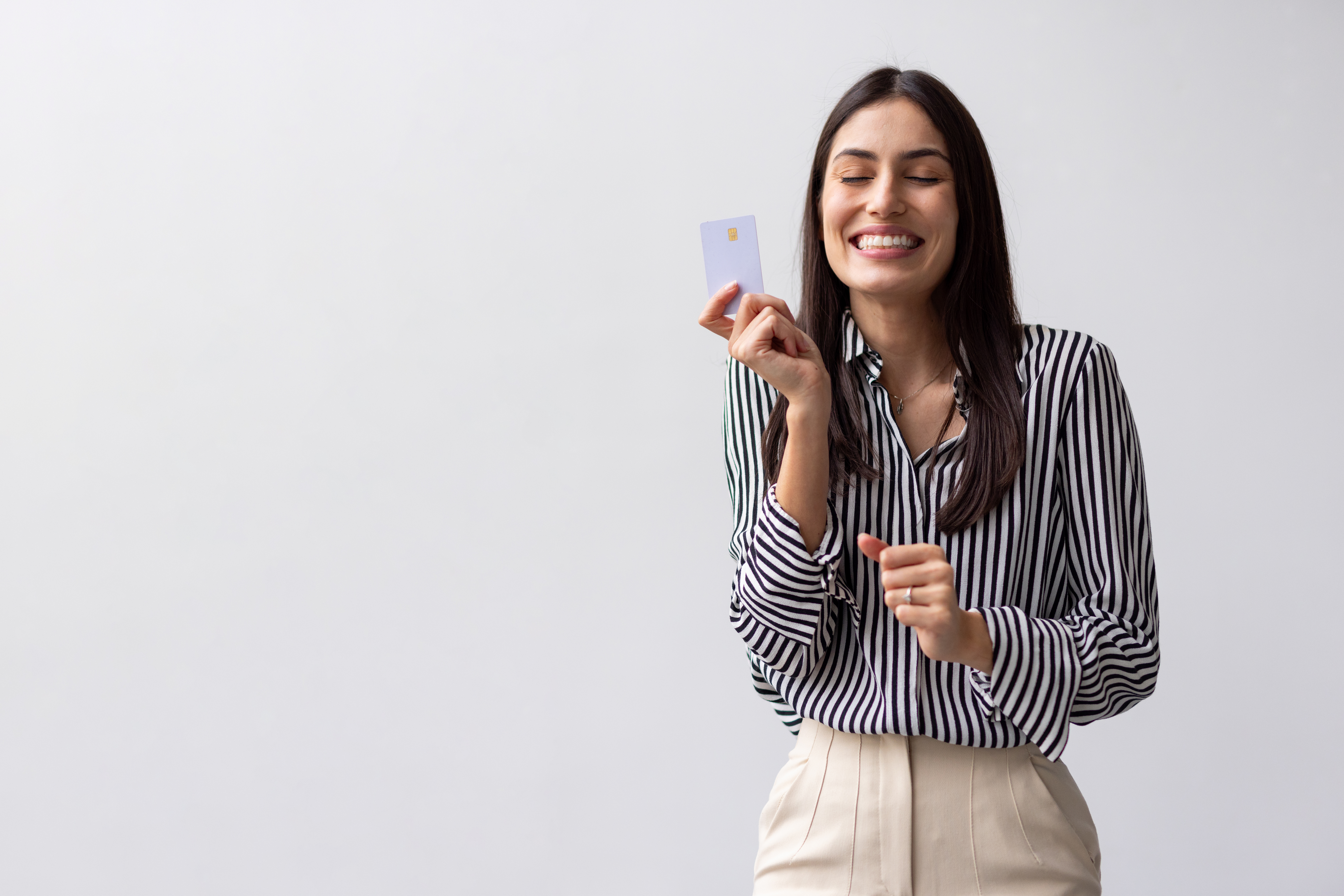 Young businesswoman holding a credit card, smiling with eyes closed, expressing joy and satisfaction